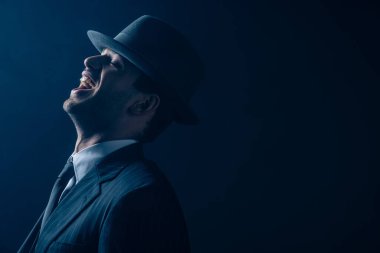 Takım elbiseli mafya üyesi ve koyu arkaplanda gülüşmeler hissetti.