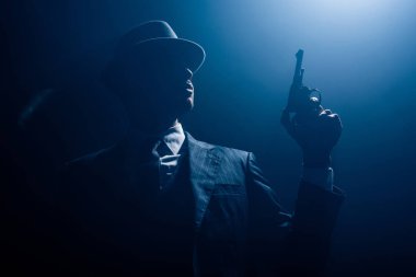 Gangster siluetinin düşük açılı görüntüsü ve karanlık arka planda sigara içmek