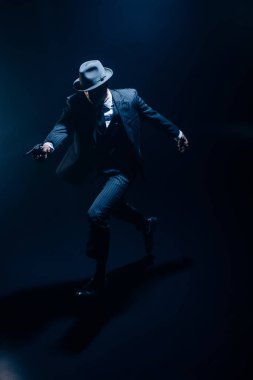 Eli silah tutan ve karanlıkta koşan bir gangster. 