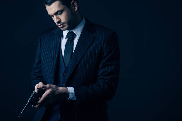 Гангстер в элегантном костюме погрузки револьвера на черном фоне
