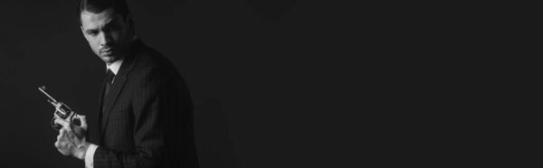Монохромное изображение гангстера с пистолетом, изолированное на черном, панорамный снимок
