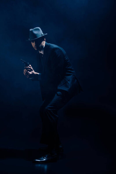 Gangster with weapon in clenched hands on dark background