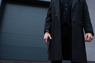 Siyah ceketli, sokakta silahlı gangsterlerin görüntüsü.