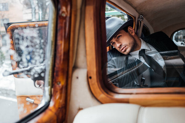 Selective focus of gangster aiming gun from retro car