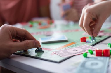KYIV, UKRAINE - JANUARY 27, 2020: cropped view of man and woman holding toy figurines while playing monopoly game clipart