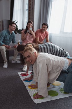 Kyiv, Ukrayna - 27 Ocak 2020: gülümseyen kız twister oyunu oynayan neşeli arkadaşlarının fotoğrafını çekiyor 