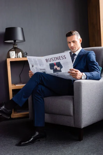 Öltönyös Üzletember Újságot Olvas Üzleti Betűkkel Karosszékben — Stock Fotó