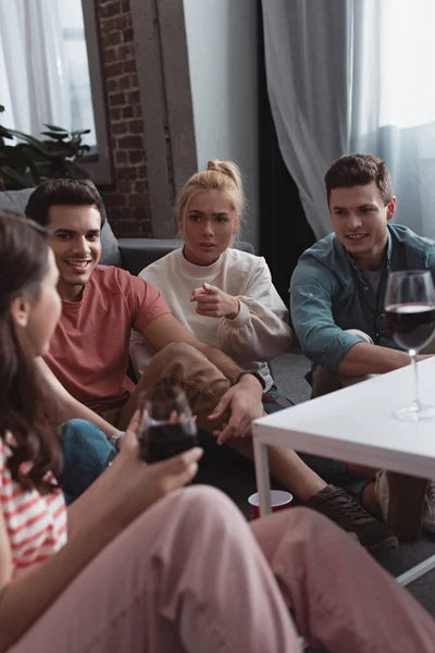 Chica Seria Señalando Con Dedo Mientras Sienta Cerca Amigos Sonrientes — Foto de Stock