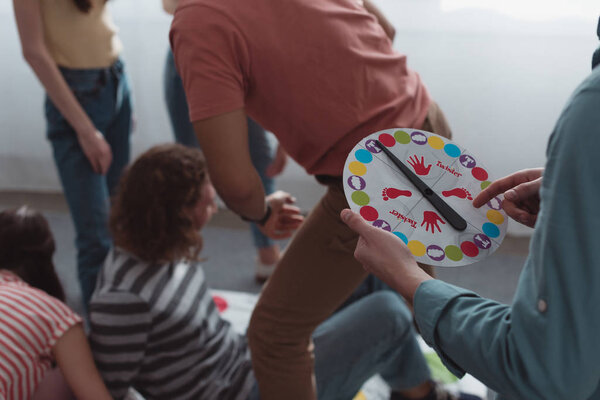 KYIV, UKRAINE - JANUARY 27, 2020: cropped view of man holding moves board near friends playing twister game