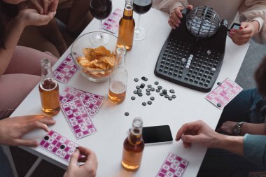 Kyiv, Ukrayna - 27 Ocak 2020: Loto topları, kartlar, çipler ve boş ekranlı akıllı telefon ile masada oturan arkadaşların görüntüsü
