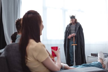 Peri kralı kostümü giymiş yakışıklı bir arkadaşa bakan arkadaşlara bakıyorum.