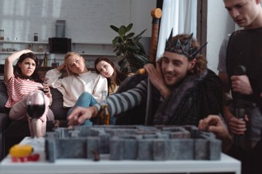Kyiv, Ukrayna - 27 Ocak 2020: Peri kostümlü erkeklerin seçici odak noktası kanepede oturan sıkılmış kızlar labirent oyunu oynarken