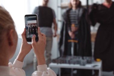 Peri kostümlü erkeklerin akıllı telefonlarda fotoğraflarını çeken seçici bir kız.