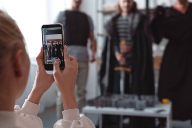 selective focus of girl taking photo of men in fairy costumes on smartphones clipart