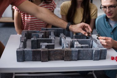 Kyiv, Ukrayna - 27 Ocak 2020: Oyuncak heykelcikler tutan genç erkekler kızların yanında labirent masa oyunu oynuyorlar