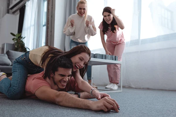 Cheerful Girl Trying Take Toy Figurine Guy Lying Floor Excited — Stock Photo, Image