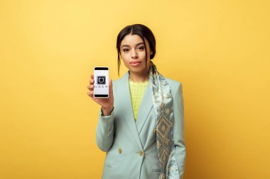 Kyiv, Ukrayna - 4 Şubat 2020: Güzel Afro-Amerikan kızı elinde süper-telefon uygulaması ile sarıyı tutuyor. 