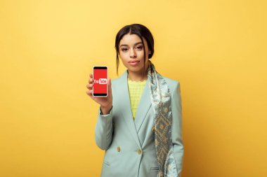 Kyiv, Ukrayna - 4 Şubat 2020: Güzel Afrikalı Amerikalı kız elinde akıllı telefon ile Youtube uygulamasını sarıya bağladı 