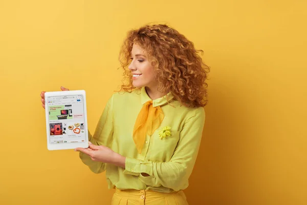 Kyiv ウクライナ 2020年2月4日 明るい赤頭の女性は黄色の上にEbayアプリでデジタルタブレットを保持 — ストック写真