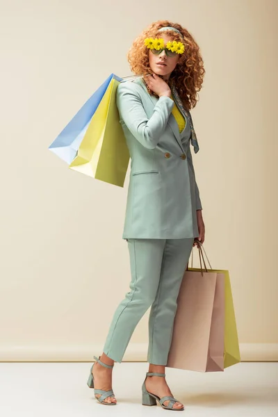 Stylish Redhead Woman Suit Sunglasses Flowers Holding Shopping Bags Beige — Stock Photo, Image