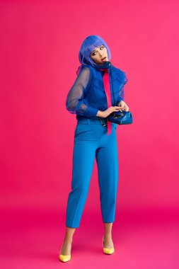 Mor peruklu endişeli kız eski telefondan konuşuyor, pembe.