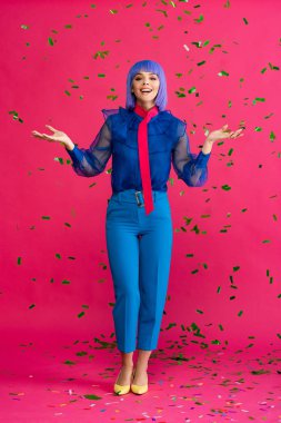 Mor peruklu güzel, heyecanlı pop sanatçısı kız. Partide konfeti, pembe üstünde.