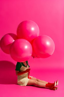 Güzel genç bir kadın pembe üzerinde balonlar tutuyor.
