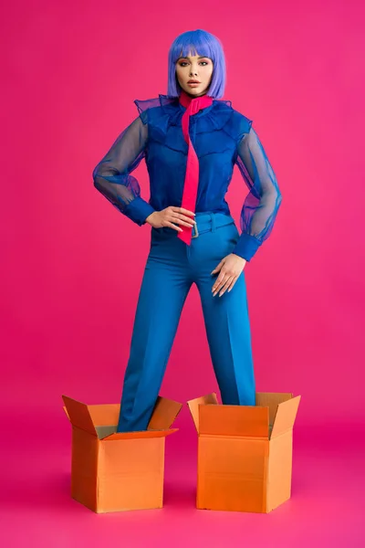 Fashionable girl in purple wig standing in cardboard boxes on pink — Stock Image Fashionable Girl Purple Wig Standing Cardboard Boxes Pink Stock Picture