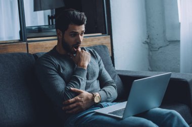 Oturma odasında kanepede oturmuş porno izleyen yakışıklı adam şok oldu.