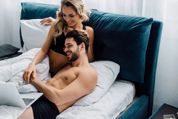 Mujer Sexy Tocando Novio Sonriente Mientras Mira Portátil Cama — Foto de Stock