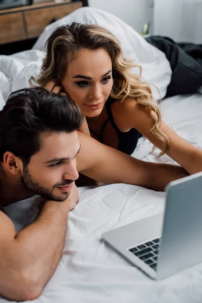 Knappe Man Zoek Naar Laptop Buurt Aantrekkelijke Vriendin Bed — Stockfoto