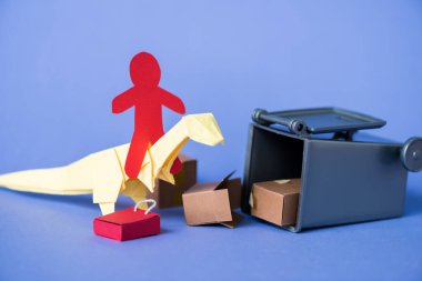 Origami dinozoru üzerinde kağıt insan çöp tenekesinin yanında ve mavi kutular üzerinde karton kutu 