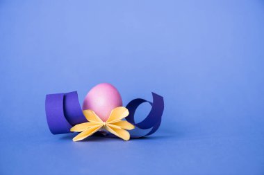 Origami çiçeği mavi üzerine boyanmış Paskalya yumurtasının yanında 