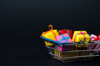 Alışveriş sepetindeki hediye kutularının seçici odağı siyah üzerine izole edilmiş 