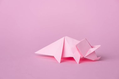 small origami rhinoceros on pink with copy space  clipart