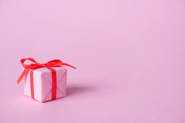 Kurdeleli küçük kağıt hediye ve pembe üzerine eğilin. 