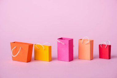 Renkli ve küçük alışveriş torbaları pembe üzerinde fotokopi alanı ile 