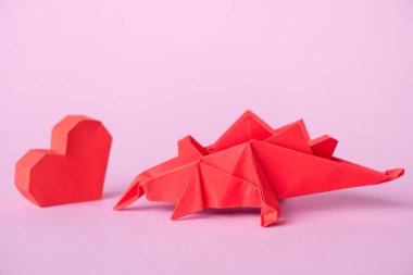 Kırmızı kağıt kalp, origami dinozorun yanında. 