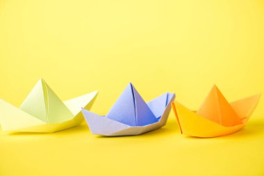 colorful paper ships on yellow with copy space  clipart