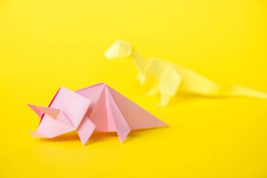 Sarı origami dinozorunun yanındaki pembe kağıt gergedanın seçici odağı 