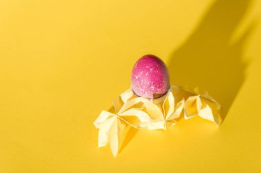 Origami çiçekleri, sarıya boyanmış Paskalya yumurtasının yanında. 