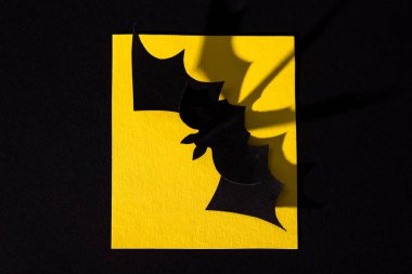 Sarı kağıt üzerindeki origami yarasasının üst görünümü siyah üzerine izole edilmiş 