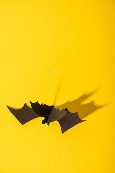 black origami bat on yellow with copy space 
