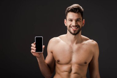 Gülümseyen seksi çıplak adam siyah ekranda boş ekranlı akıllı telefon gösteriyor. 
