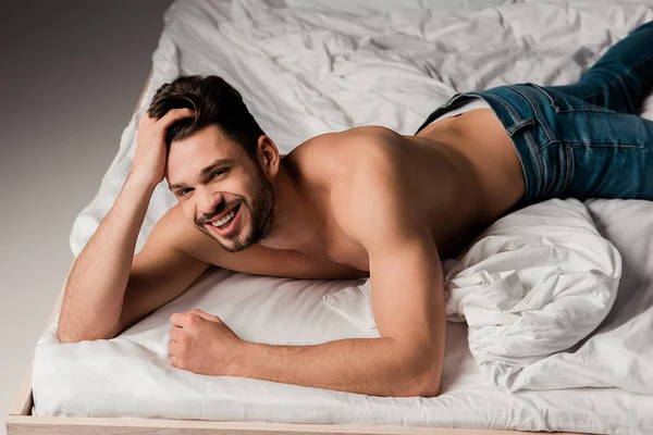 Gülümseyen Üstsüz Kot Pantolonlu Sakalsız Bir Adam Griye Yatmış Yatıyor — Stok fotoğraf