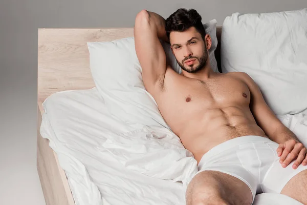 Bärtiger Schöner Mann Liegt Auf Bett Auf Grau — Stockfoto