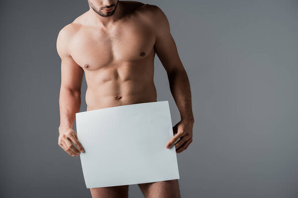 cropped view of sexy naked man holding empty board isolated on grey