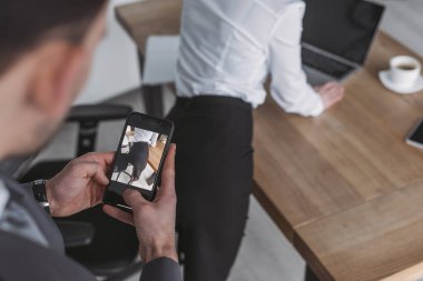 Akıllı telefondan sekreterin kalçalarının fotoğrafını çeken işadamlarının seçici odak noktası