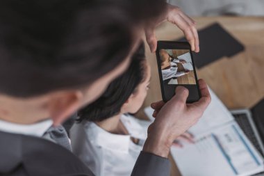 Akıllı telefondan sekreterin göğüslerinin fotoğrafını çeken işadamlarının seçici odak noktası