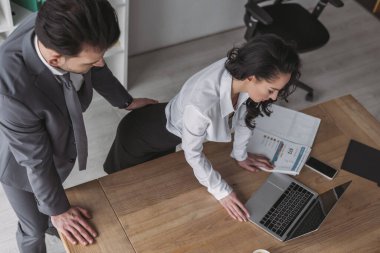 high angle view of businessman touching buttocks of secretary standing at workplace clipart